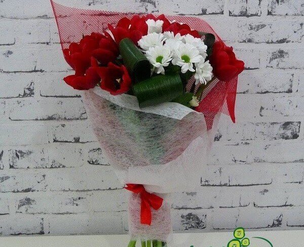 Букет из белых хризантем, красных тюльпанов и аспидистры в красной сетке фото
