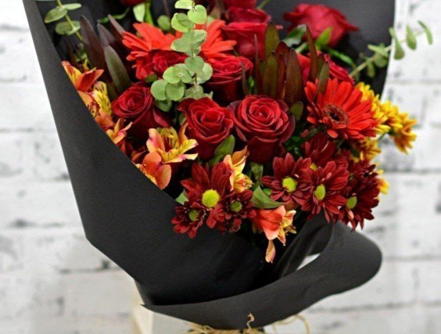 Букет из красных роз, гербер, хризантем, оранжевых альстромерий, желтых хризантем и эвкалипта в черной бумаге фото