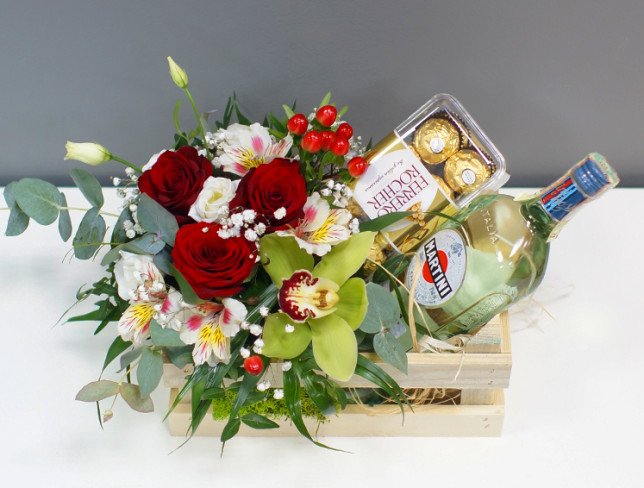 Wooden box with roses, hypericum, cymbidium orchid, alstromeria, Martini bottle and candy photo