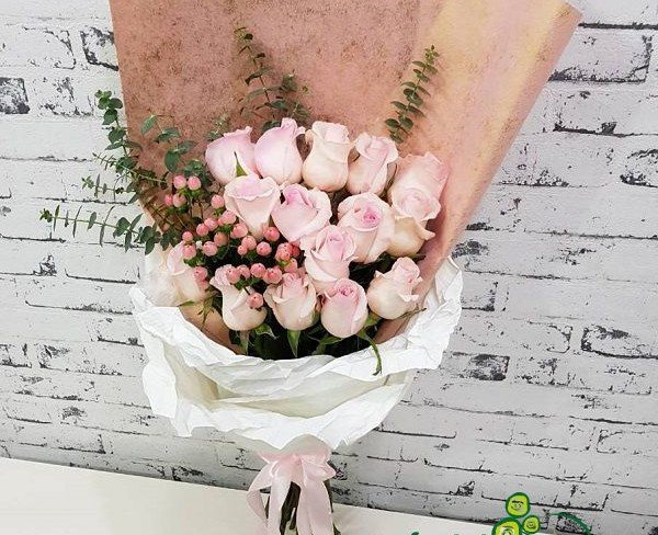 Buchet de trandafiri roz, hypericum și eucalipt în hârtie albă cu panglică roz - Foto
