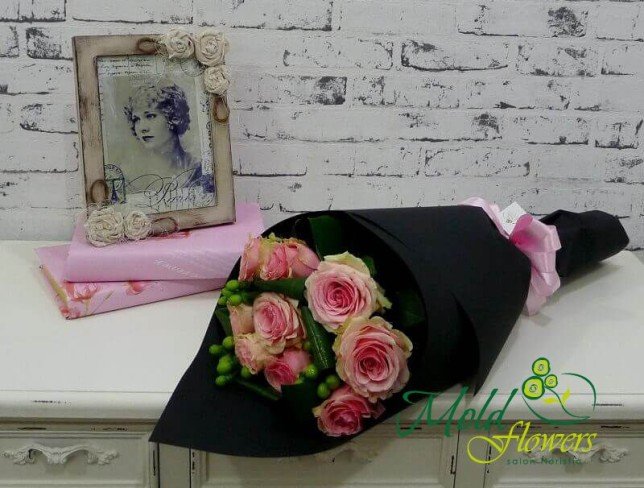 Buchet de trandafiri roz și hypericum verde în hârtie neagră cu panglică roz foto