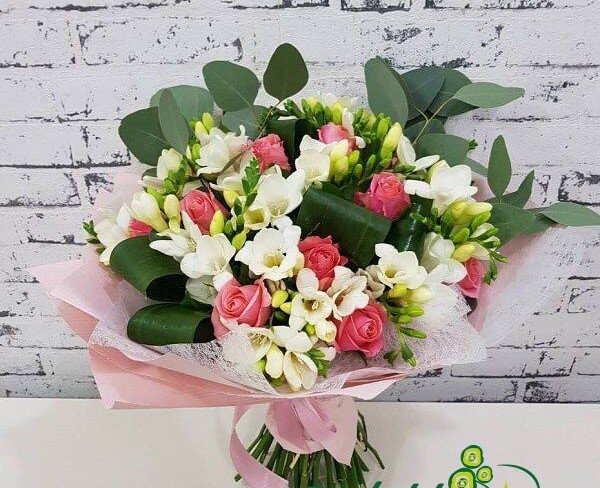 Bouquet of pink roses, white freesias, aspidistra in pink paper photo
