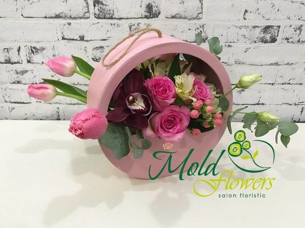 Круглая розовая коробка с розовыми розами, тюльпанами, гиперикумом, белой эустомой, бордовой орхидеей цимбидиум и эвкалиптом фото