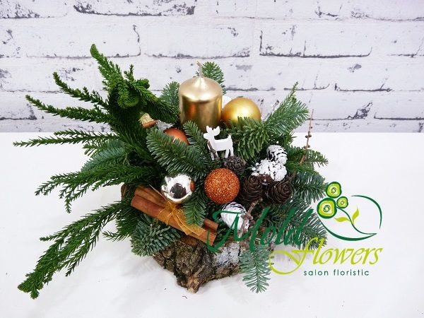 Winter composition on a stump with sprigs of spruce, cinnamon, cones, gold and bronze Christmas tree toys and a gold-colored candle photo