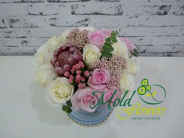 Blue box with white and pink roses, protea, pink hypericum, and eucalyptus photo