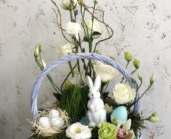 Basket with white roses, eustoma, cymbidium orchid, oats, decorative hare, nest and candle photo