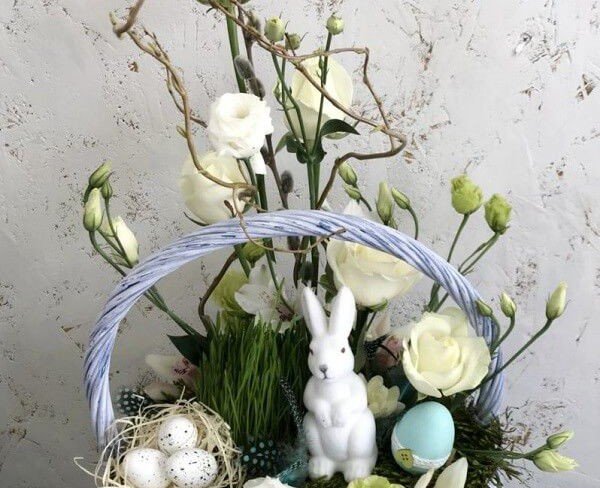 Basket with white roses, eustoma, cymbidium orchid, oats, decorative hare, nest and candle photo