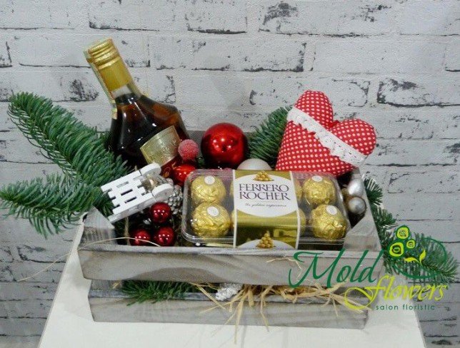 Wooden box with candies Ferrero rocher, cognac Kvint, fir branches, Christmas toys, cones photo
