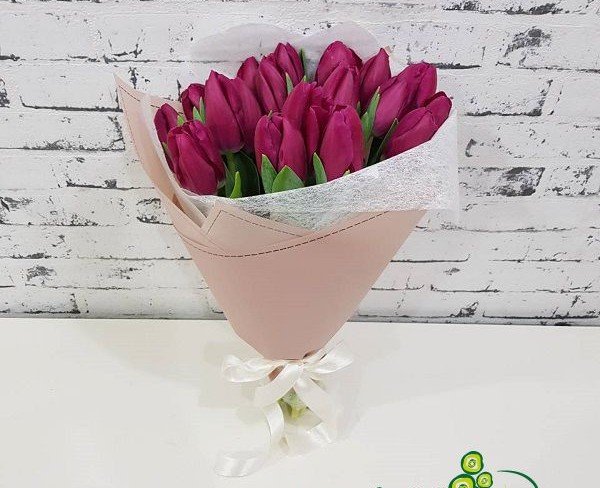 Bouquet of purple tulips in pink paper and white netting photo