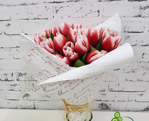 Bouquet of red and white tulips in white paper with inscriptions photo