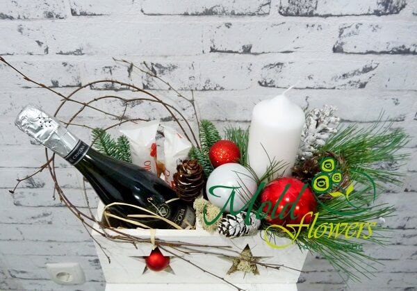 White box with a bottle of champagne, Raffaello candy, white candle, pinecones, Christmas toys photo