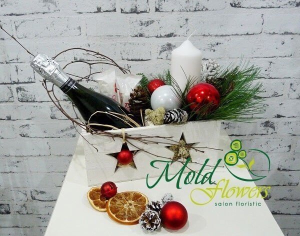 White box with a bottle of champagne, Raffaello candy, white candle, pinecones, Christmas toys photo