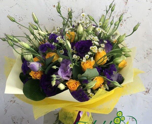 Bouquet of yellow roses, daisies, purple statice, eustoma in yellow wrapper photo