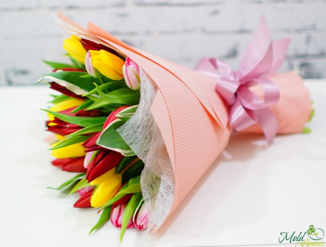 Букет из желтых, красных и розовых тюльпанов в розовой бумаге фото