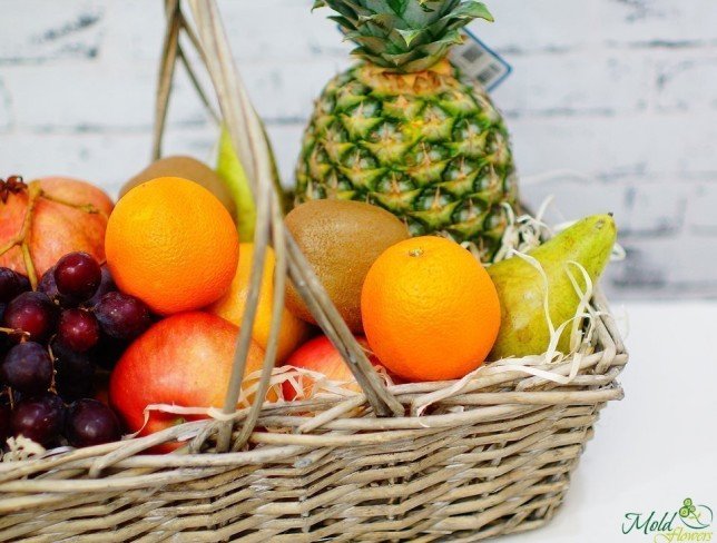 Basket with red grapes, pineapple, oranges, pears, pomegranate, kiwi photo