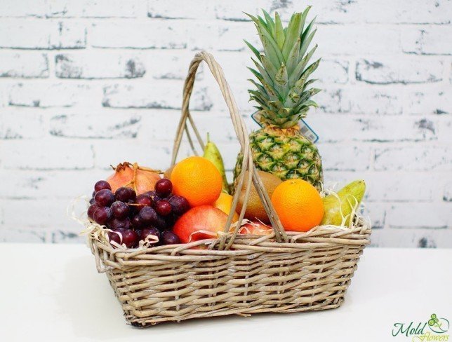 Basket with red grapes, pineapple, oranges, pears, pomegranate, kiwi photo