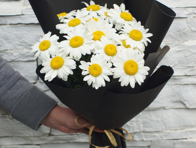 Bouquet of chamomile flowers in black paper photo