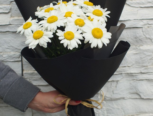 Bouquet of chamomile flowers in black paper photo