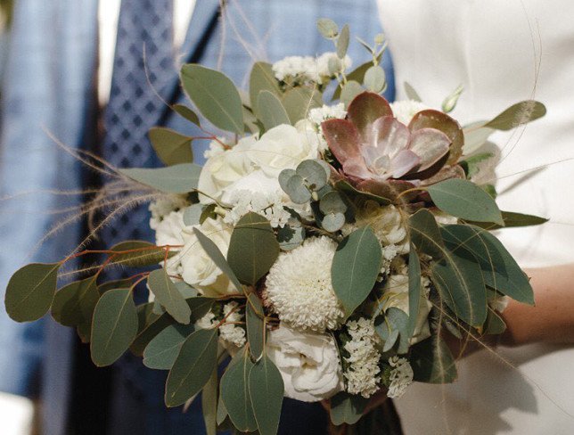 The bride's bouquet made of white rose, lisianthus, eucalyptus, and stone rose photo