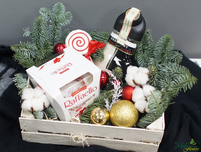 Wooden box with candy, Sheridans bottle, pinecones, Christmas toys, spruce branches photo