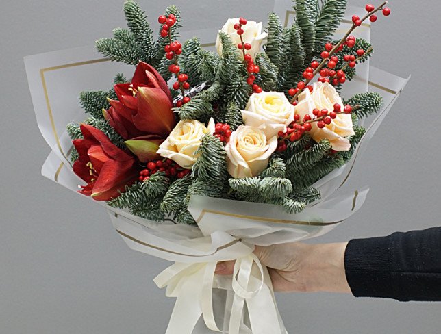 Buchet din ramuri de brad, amaryllis rosii, trandafiri crem si fructe decorative, intr-o hartie alba, legat cu o panglica alba