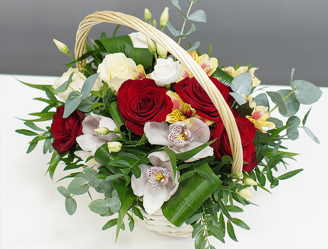 White basket with white roses and orchids, eustomas, alstromeria, red roses, eucalyptus, aspidistra photo