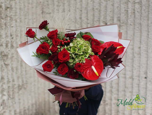 Bouquet of red roses, anthurium, green hydrangeas, and exotic leaves, wrapped in white and pink paper