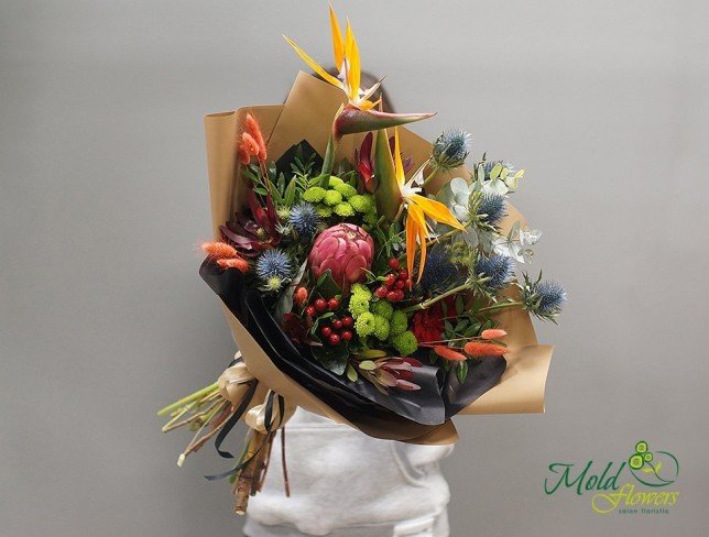 Pink protea bouquet, orange strelitzia, blue eryngium, green chrysanthemums, in brown and black paper