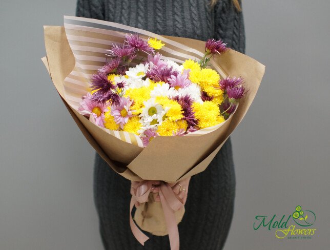 Bouquet with yellow, purple, and white chrysanthemums, wrapped in brown paper with white stripes, tied with a pink ribbon