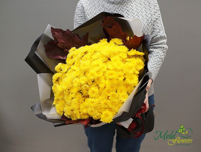 Bouquet with yellow chrysanthemums, decorated with red leaves, in black and white paper