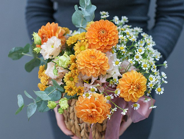 Basket with orange dahlias and chamomile photo