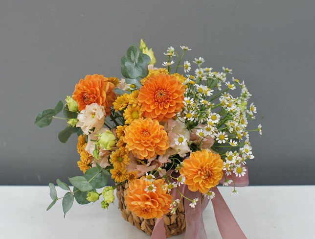 Basket with orange dahlias and chamomile photo