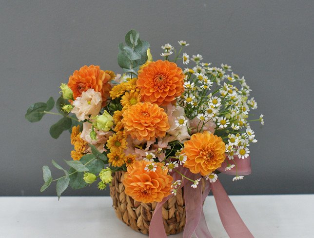 Basket with orange dahlias and chamomile photo