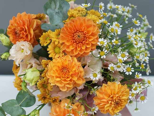 Basket with orange dahlias and chamomile photo